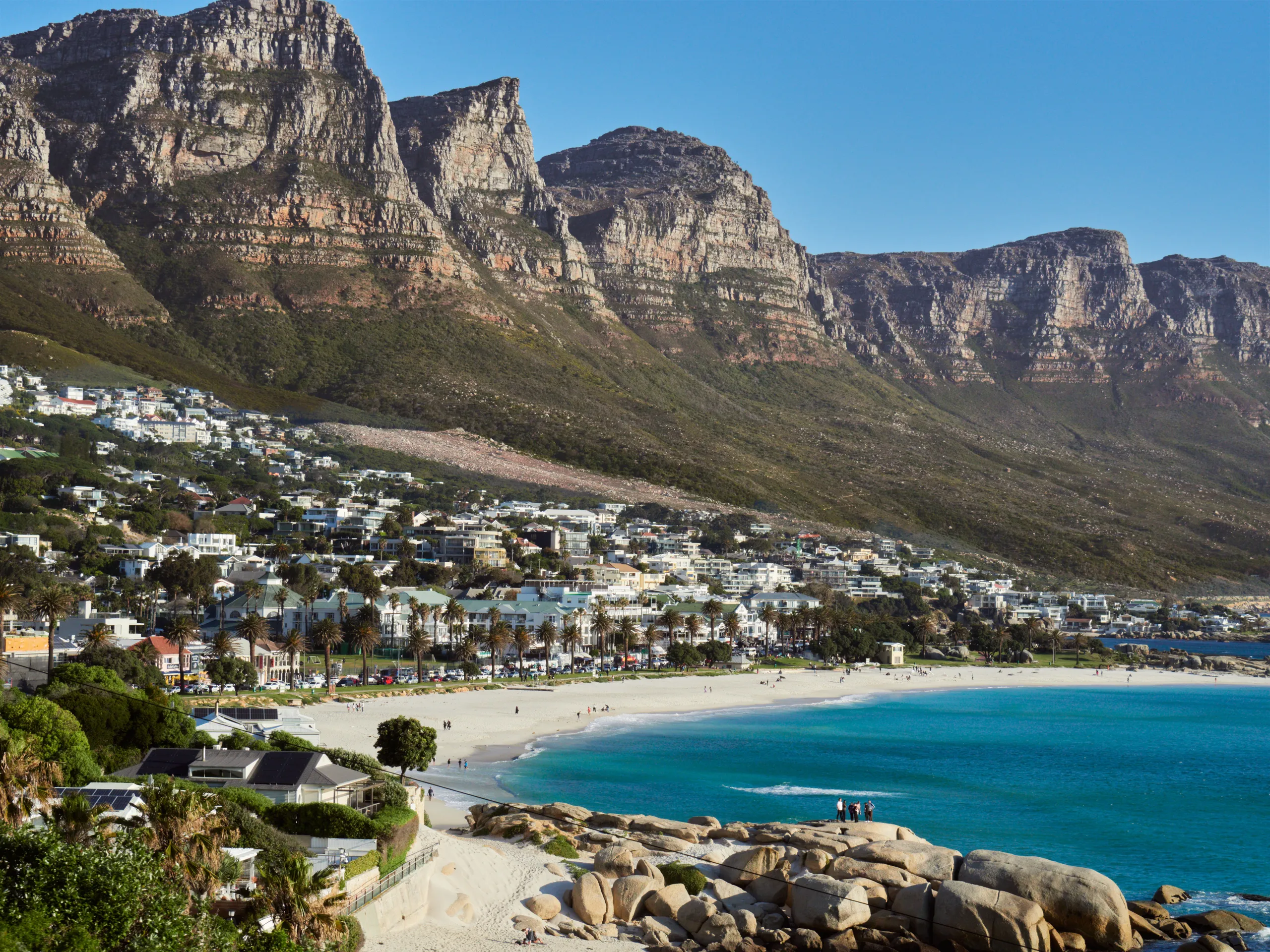 Camps Bay from above: the promenade, the white beach, the boulders and the Twelve Apostles ridge behind